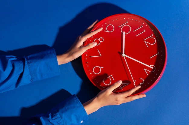 Hände halten Stillleben mit einer Wanduhr