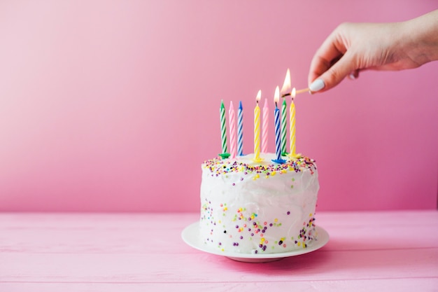 Hände leuchten Kerzen auf Kuchen