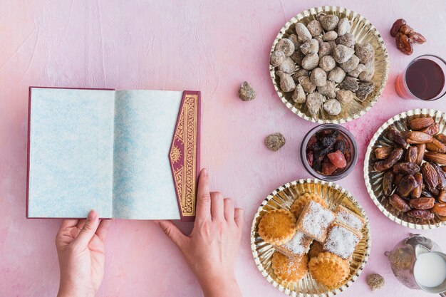 Kostenloses Foto hände mit koran bei tisch mit süßigkeiten