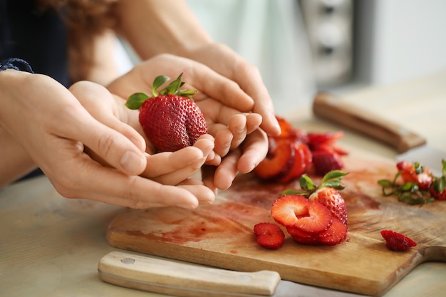 Hände schneiden frische Erdbeeren