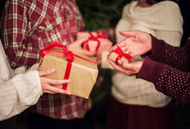 Hände von Leuten, die Geschenke für Weihnachten austauschen