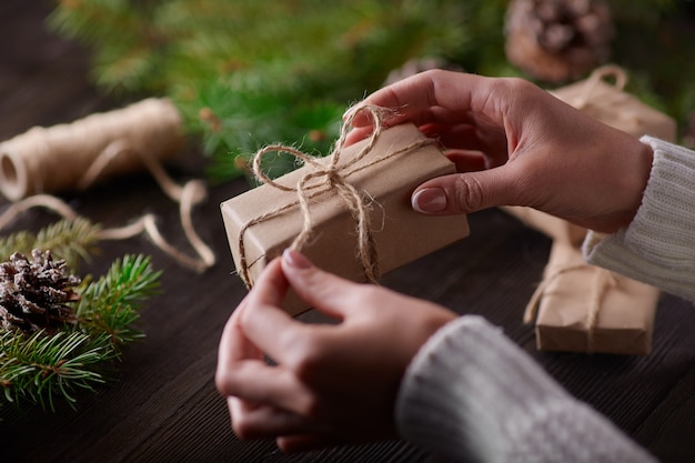 Hände, welche die Knoten der Schnur von Geschenk-Pakete binden