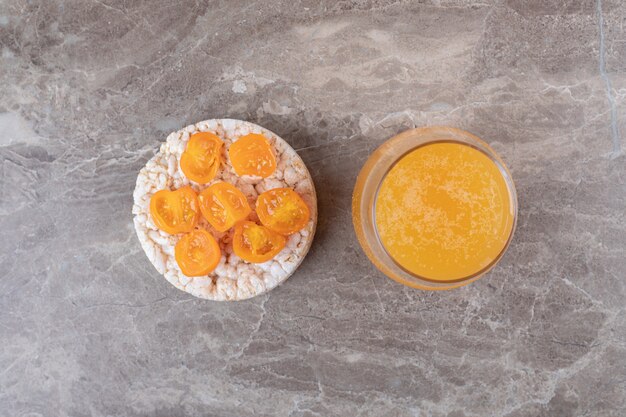 Haferbrei mit Tomatenscheiben in einem Glas neben Orangensaft auf der Marmoroberfläche