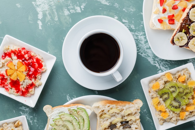 Haferflocken mit Früchten, Marmelade, Sandwich, Kaffee in Tellern