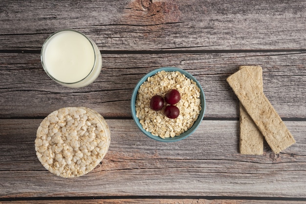 Haferflockencracker, Körner mit Beeren und eine Tasse Milch auf dem Tisch, Draufsicht