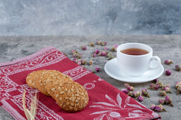 Haferkekse und eine Tasse schwarzen Tee auf Marmoroberfläche.