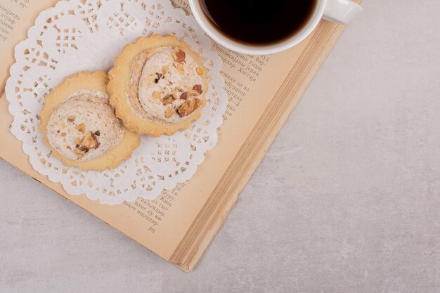Haferkekse und eine Tasse Tee auf offenem Buch.