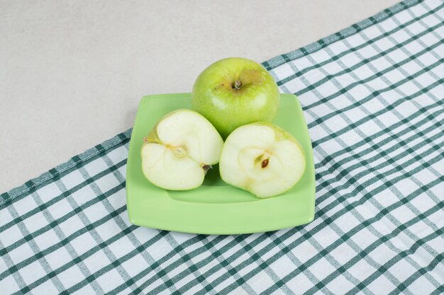 Halb geschnittene grüne Äpfel auf grünem Teller