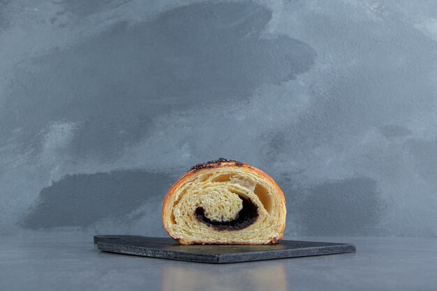 Halb geschnittenes Croissant mit Schokolade auf schwarzem Brett.