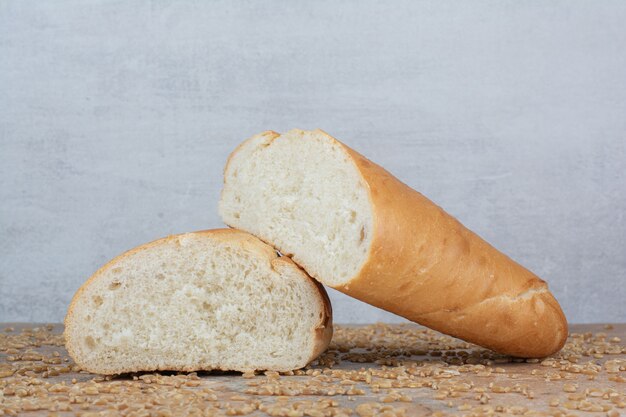 Halb geschnittenes Weizenbrot mit Gerste auf Marmortisch