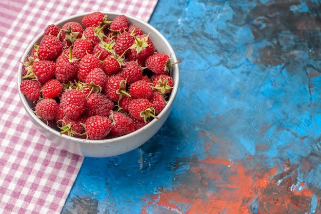 Halbe Draufsicht rote Himbeeren innerhalb der Platte auf blauem Hintergrund Fotogeschmack Sommerfarbe wilde Baumbeere