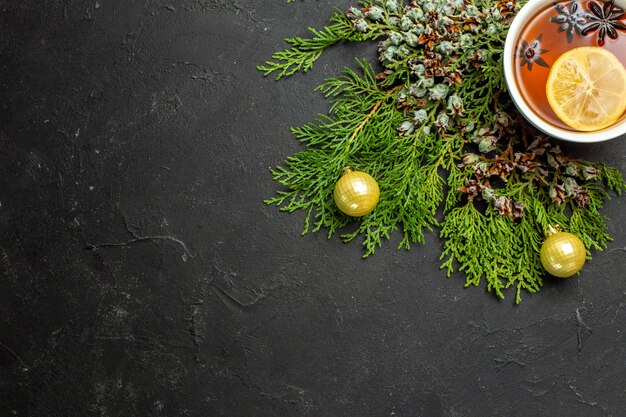 Halber Schuss einer Tasse Schwarztee-Weihnachtszubehör und Zimtlimetten auf schwarzem Hintergrund