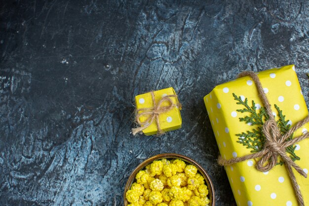 Halber Schuss frischer Zitronen mit Blättern und gelben Geschenkbox-Keksen in einem braunen Topf auf dunklem Hintergrund