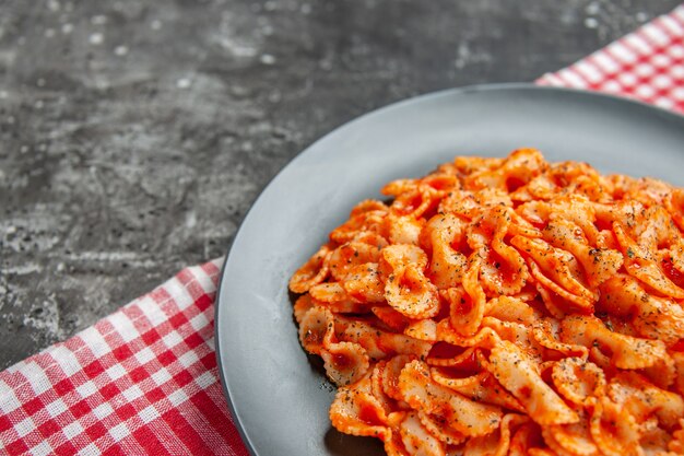 Halber Schuss köstliche Pasta-Mahlzeit auf einem schwarzen Teller zum Abendessen auf einem rot gestreiften Handtuch to