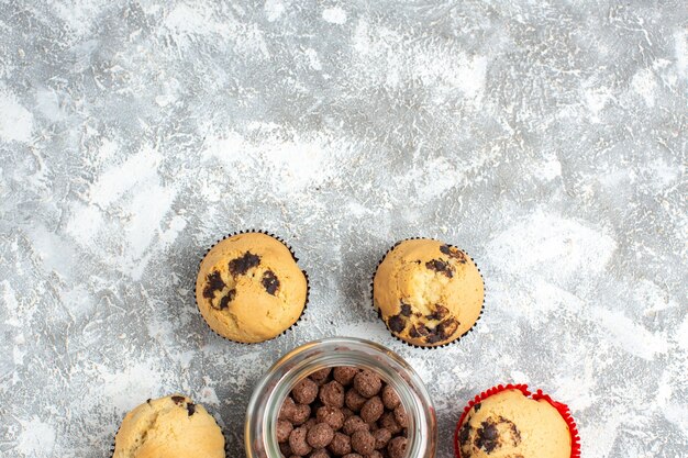 Halber Schuss köstlicher kleiner Cupcakes und Schokolade in einem Glastopf neben einem Weihnachtsgeschenk auf dem Eistisch