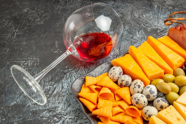 Kostenloses Foto halber schuss leckeren besten snacks auf einem braunen tablett und gefallenem weinglas auf grauem hintergrund