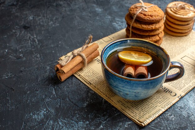 Halber Schuss Teezeit mit gestapelten leckeren Keksen Zimt Zitrone auf einer alten Zeitung auf dunklem Hintergrund