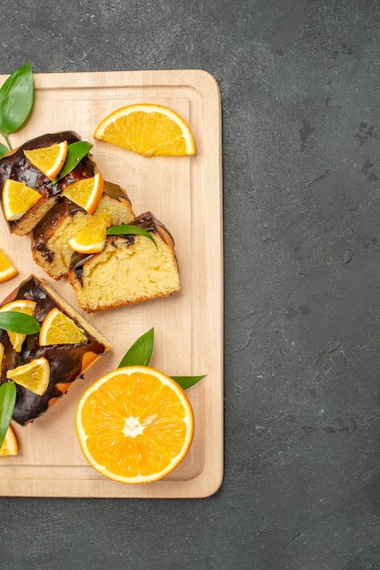 Halber Schuss von frischen Orangenscheiben und gehackten Kuchenscheiben auf dunklem Tisch