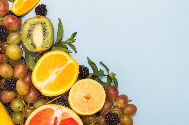 Halbierte Zitrusfrüchte; Kiwi; Brombeere und Trauben auf blauem Hintergrund