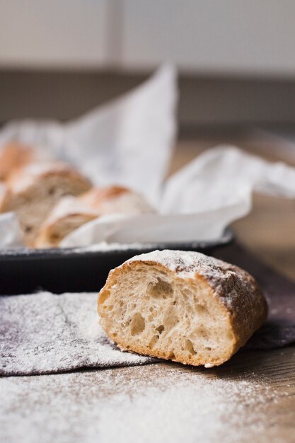 Halbiertes gebackenes Brot mit Mehl auf Holztisch