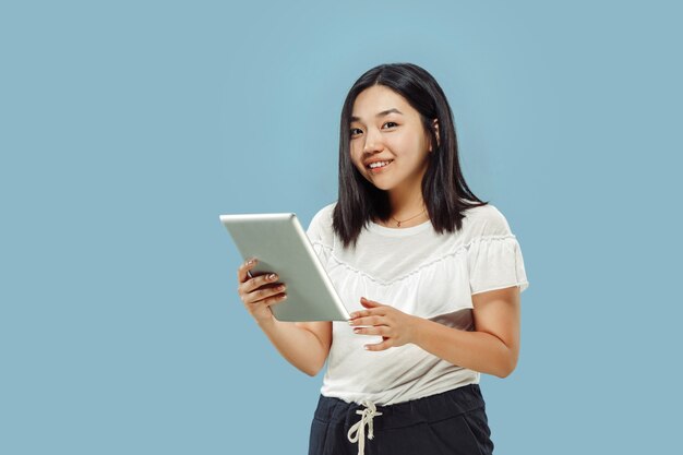 Halblanges Porträt der koreanischen jungen Frau auf blauem Studio