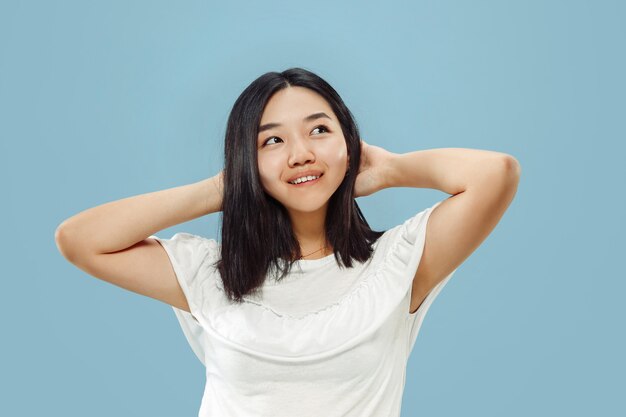 Halblanges Porträt der koreanischen jungen Frau. Weibliches Modell im weißen Hemd. Ausruhen und lächeln. Konzept menschlicher Emotionen, Gesichtsausdruck. Vorderansicht.