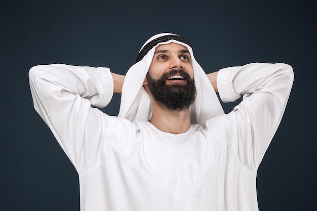 Halblanges Porträt des arabischen saudischen Geschäftsmannes auf Dunkelblau
