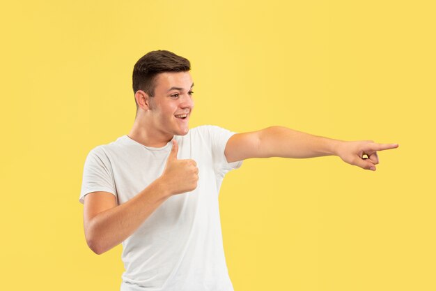 Halblanges Porträt des kaukasischen jungen Mannes auf gelbem Studio