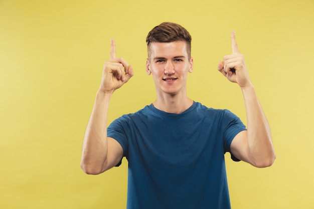 Halblanges Porträt des kaukasischen jungen Mannes auf gelbem Studio