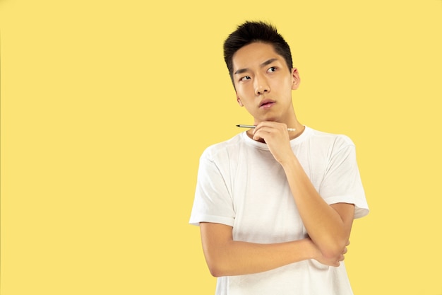 Halblanges Porträt des koreanischen jungen Mannes auf Gelb