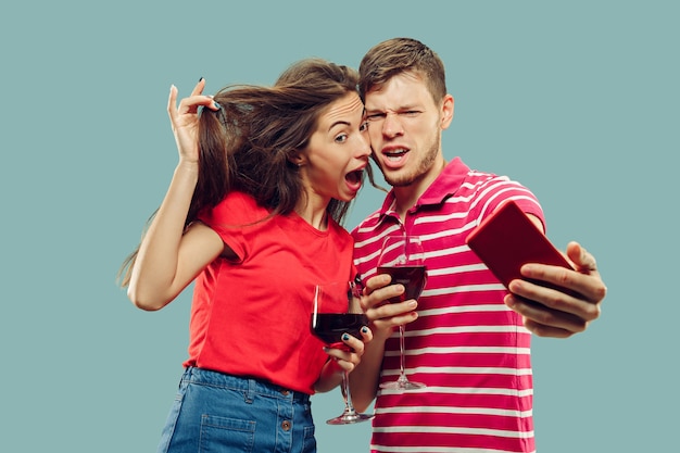 Halblanges Porträt des schönen jungen Paares lokalisiert. Lächelnde Frau und Mann, die Gläser mit Wein halten und Selfie machen. Gesichtsausdruck, Sommer, Wochenendkonzept.