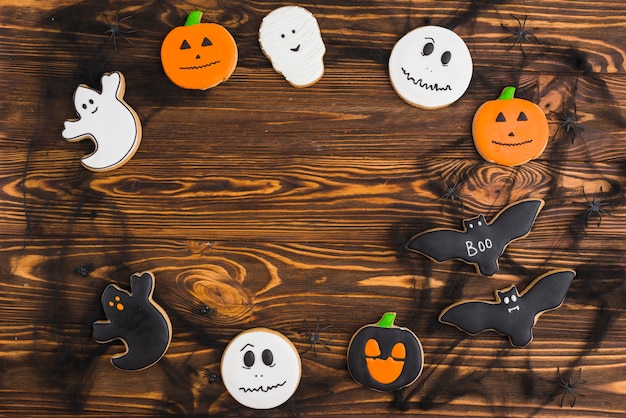 Kostenloses Foto halloween-pfefferkuchen vereinbarten im kreis auf hölzernem hintergrund