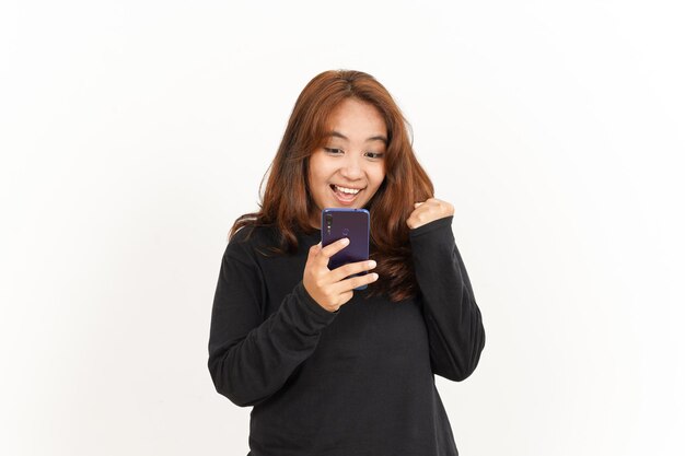 Halten und verwenden des smartphones einer schönen asiatischen frau, die ein schwarzes hemd, isoliert auf weiss, trägt