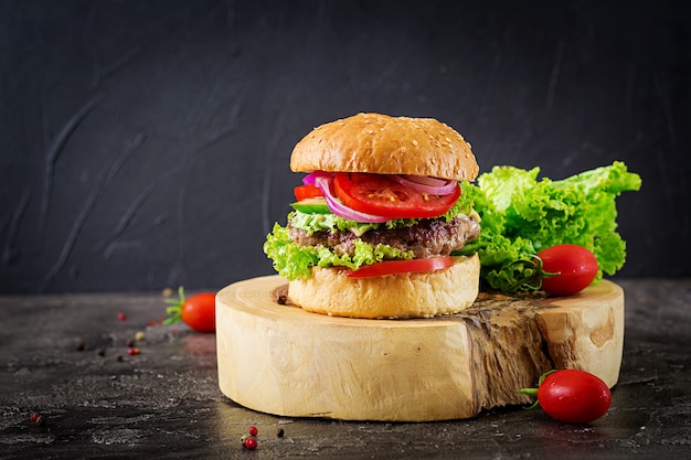 Hamburger mit Rindfleischburger und frischem Gemüse auf dunklem Tisch. Leckeres Essen.