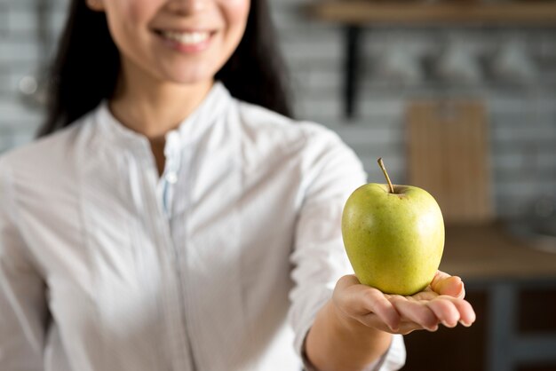 Hand der Frau, die grünen Apfel zeigt