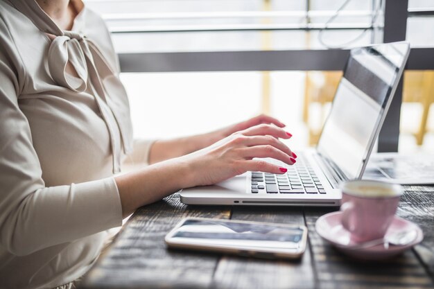 Hand der Frau, die Laptop auf Holztisch verwendet