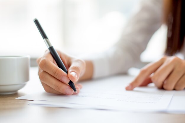 Hand der Geschäftsfrau schriftlich auf Papier im Büro