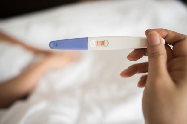 Hand der jungen Frau, die Schwangerschaftstest hält
