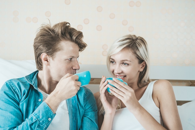 Hand des glücklichen Paars, die morgens Schale hält und Kaffee trinkt