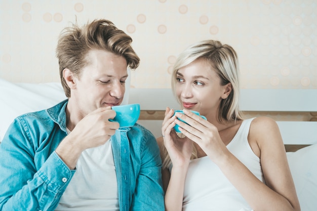 Hand des glücklichen Paars, die morgens Schale hält und Kaffee trinkt