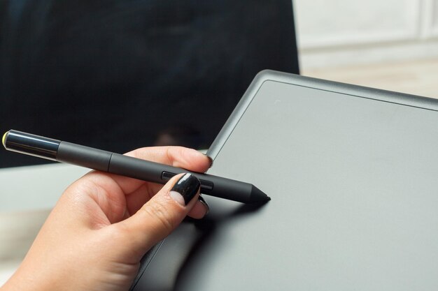 Hand des Grafikdesigners, der mit Stilus und Tablet arbeitet