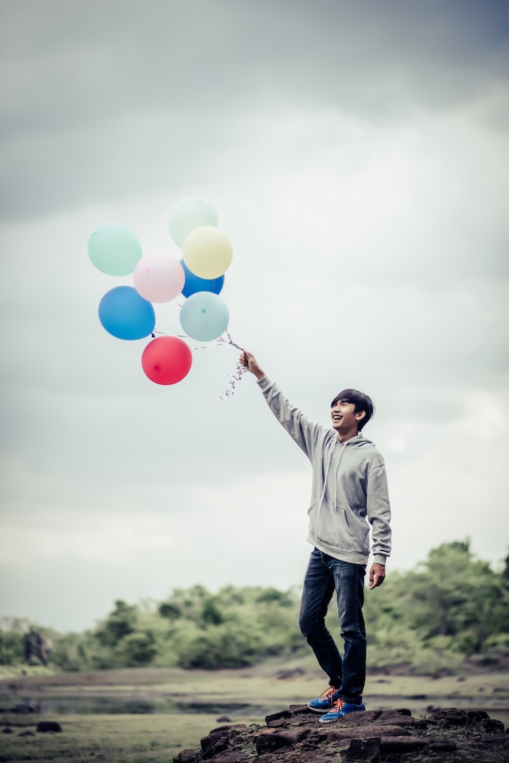 Kostenlose Foto hand des jungen mannes, die bunte ballone hält