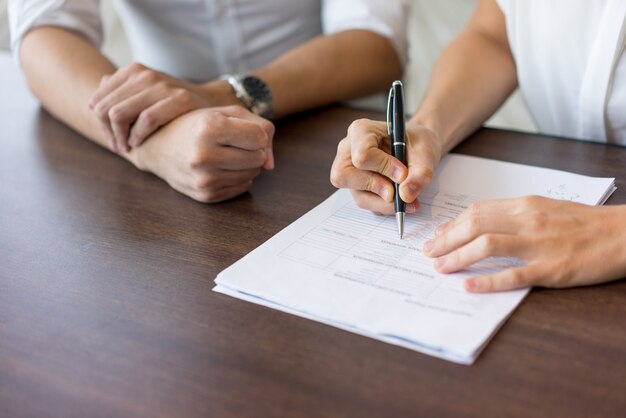 Hand des weiblichen Stunden-Managers, der Form am Interview mit männlichem Kandidaten ausfüllt.