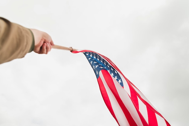Kostenloses Foto hand, die amerikanische flagge im himmel wellenartig bewegt