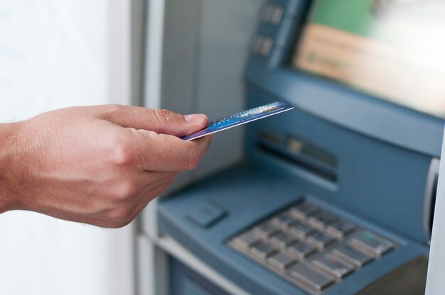 Hand, die ATM-Karte in Bankmaschine einfügt, um Geld zurückzuziehen. Geschäftsmann Männer Hand setzt Kreditkarte in Geldautomaten