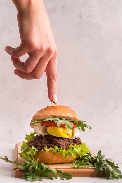 Hand, die auf einen köstlichen Hamburger zeigt