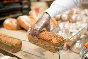 Kostenloses Foto hand, die brot auf unscharfem hintergrund hält