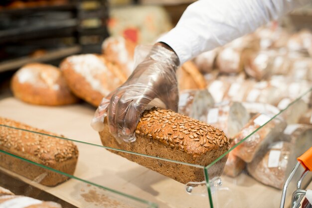 Hand, die Brot auf unscharfem Hintergrund hält