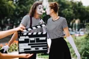 Kostenloses Foto hand, die clapperboard vor liebevollen pantomimepaaren hält