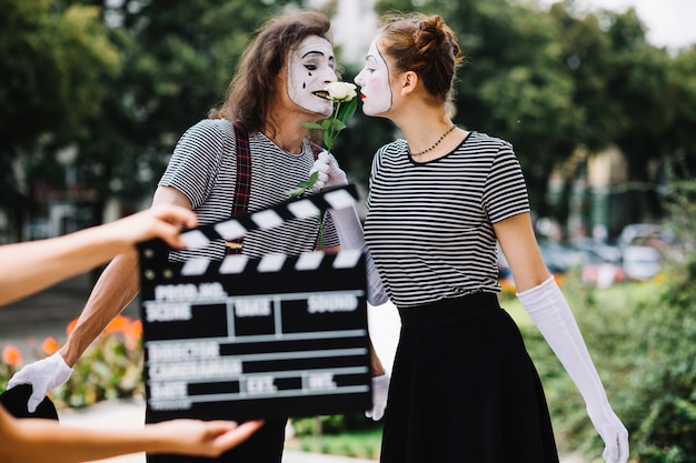 Hand, die clapperboard vor liebevollen Pantomimepaaren hält